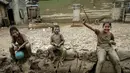 Desa ini menjadi perhatian publik karena merupakan salah satu wilayah yang terdampak paling parah akibat bencana banjir bandang di Sumatera. Tampak dalam foto, Baiti Arafah (kanan) menunggu distribusi bantuan bersama yang lain di Babo, Aceh Tamiang, pada Senin 15 Desember 2025. (Yasuyoshi Chiba/AFP)