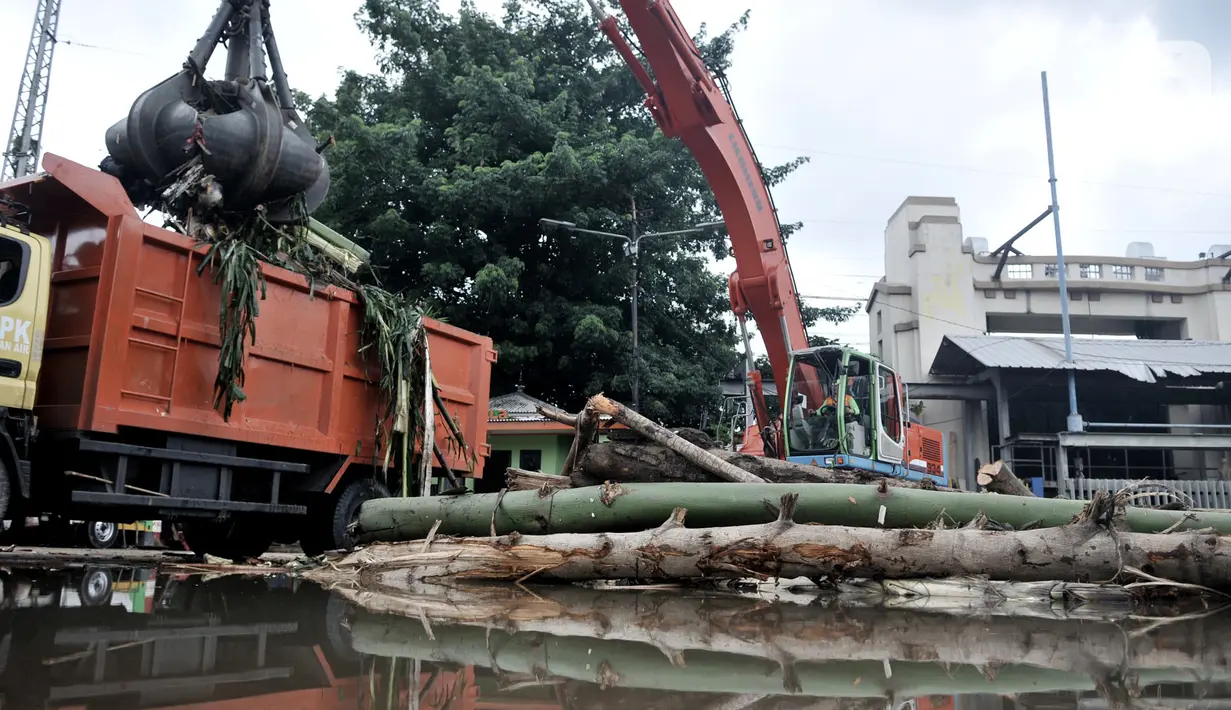 Petugas menggunakan alat berat saat mengangkut tumpukan sampah kiriman di Pintu Air Manggarai, Jakarta, Minggu (29/12/2019). Volume sampah di Pintu Air Manggarai mencapai 84 meter kubik atau setara tujuh truk. (merdeka.com/Iqbal Nugroho)