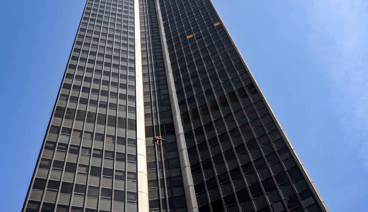 Alain Robert, pendaki bangunan pencakar langit asal Prancis memanjat Menara Montparnasse di Paris, Prancis, Rabu (12/10/2022). Alain Robert yang dikenal sebagai Spiderman Prancis itu kembali beraksi dengan memanjat Menara Montparnasse yang memiliki ketinggian 210 meter. (Bertrand GUAY/AFP)