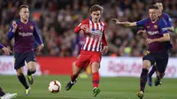 Striker Atletico Madrid, Antoine Griezmann, berusaha melewati pemain Barcelona pada laga La Liga di Stadion Camp Nou, Sabtu (6/4). Barcelona menang 2-0 atas Atletico Madrid. (AP/Manu Fernandez)