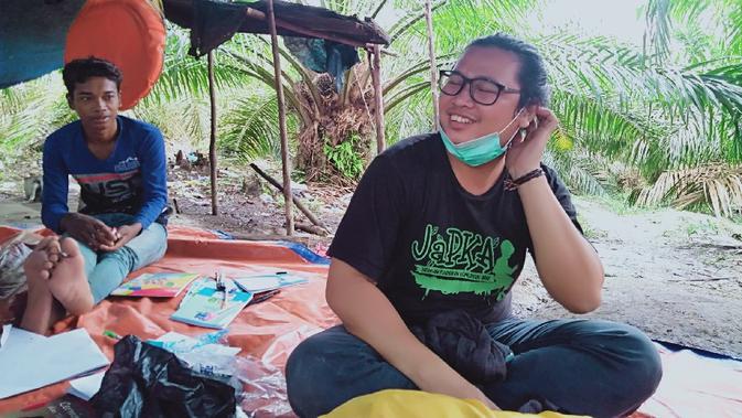 Fasilitator pendidikan KKI Warsi, Jauhar Maknun (kanan), saat melihat proses belajar orang rimba di wilayah Makekal Ilir, Tebo, Jambi, Kamis (19/11/2020). (Liputan6.com/Gresi Plasmanto)
