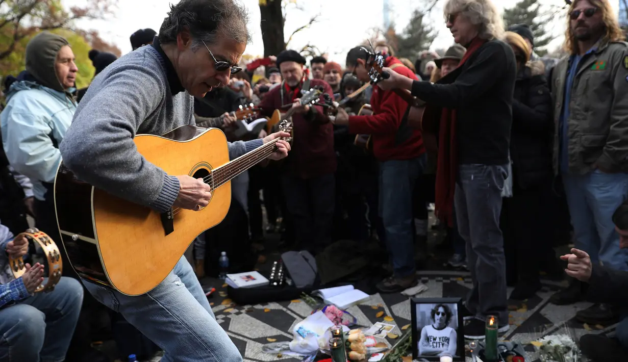 Sejumlah musisi bermain gitar dan bernyanyi saat memperingati 36 tahun kematian John Lennon di New York, AS (8/12). Lennon dikenal sebagai penyanyi, pencipta lagu, penulis, dan aktivis politik yang terkenal di seluruh dunia. (Reuters/Mark Kauzlarich)