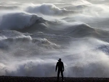 Seseorang melihat ke arah ombak yang menerjang pantai di Newhaven pada tanggal 2 Januari 2024. (ADRIAN DENNIS/AFP)