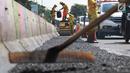 Petugas Bina Marga Pasar Minggu menambal jalan yang rusak di Jalan Raya Ragunan, Jakarta, Senin (22/4). Petugas mengaku bahwa keberadaan beton pembatas jalan justru membuat jalan di kawasan tersebut selalu rusak setiap hujan deras karena menimbulkan genangan air. (Liputan6.com/Immanuel Antonius)