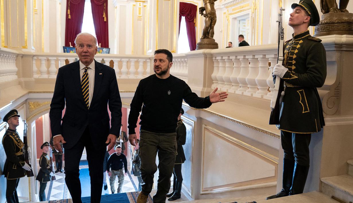 Presiden Joe Biden (kiri) bersama Presiden Ukraina Volodymyr Zelensky menaiki tangga di Istana Mariinsky, Kyiv, Ukraina pada tanggal 20 Februari 2023. Presiden AS Joe Biden menjanjikan peningkatan pengiriman senjata untuk Ukraina selama kunjungan mendadak ke Kyiv pada 20 Februari 2023, di mana ia juga menjanjikan komitmen Washington dalam membela integritas teritorial Ukraina. (Evan Vucci/POOL/AFP)