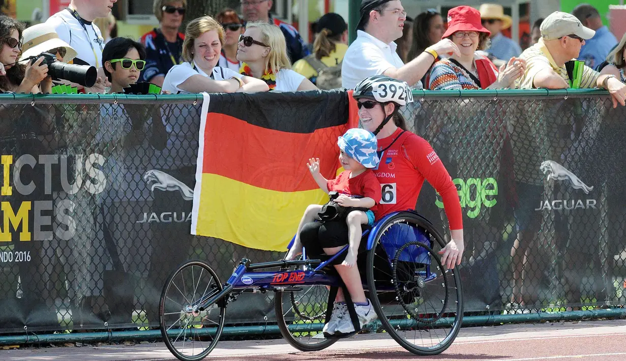Seorang peserta mendapat sambutan hangat dari penonton saat menggendong anaknya  pada ajang Invictus Games Orlando 2016 di ESPN Wide World of Sports complex, (10/5/2016), Lake Buena Vista, Florida.   (Gerardo Mora/Getty Images for Invictus Games/AFP)