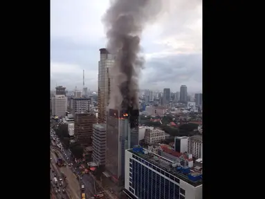 Api disertai asap pekat masih membubung di atas Gedung Wisma Kosgoro di Jalan MH Thamrin, Jakarta Pusat hingga pagi ini, Selasa (10/3/2015). (twitter.com/Peddy_Robot)