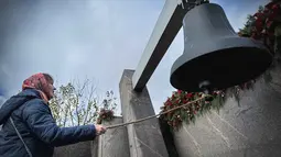Seorang perempuan membunyikan lonceng saat mengunjungi monumen peringatan bagi para korban represi politik di Butovo, di luar Moskow, pada Kamis 30 Oktober 2025, menandai hari peringatan. Untuk diketahui, situs ini merupakan kuburan massal bagi lebih dari 20.000 orang yang dieksekusi secara rahasia selama kampanye pembersihan politik Stalin antara tahun 1937 dan 1938. (Nikita BORISSOV/AFP)