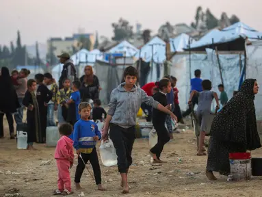 Orang-orang mengisi wadah air mereka di kamp Nuseirat untuk pengungsi Palestina di Jalur Gaza tengah pada Kamis 4 Desember 2025. Hingga saat ini, akses bantuan air bersih di kamp pengungsi Nuseirat di Jalur Gaza tengah masih sangat terbatas. (Eyad Baba/AFP)