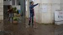 Seorang pria yang menyapu air dari sebuah gedung menunjukkan ketinggian yang dicapai air saat jalan dibanjiri semalaman di Alges, tepat di luar Lisbon, Selasa (13/12/2022). Badai Atlantik menghantam semenanjung Iberia, meninggalkan jejak kehancuran pada Selasa, terutama di Ibu kota Portugal,  Lisbon, sebelum pindah ke timur ke Spanyol.  (AP Photo/Armando Franca)