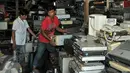Nurcholis Agi (kiri) bersama pekerjanya saat merapihkan tumpukan barang-barang elektronik bekas disudut ruangan toko Mal Rongsok, Depok, Rabu (17/2). (Liputan6.com/Yoppy Renato)