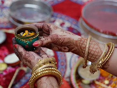 Seorang wanita Hindu yang sudah menikah melakukan ritual festival Karva Chauth di Ahmadabad,  Kamis (17/10/2019). Selama festival Karva Chauth, wanita-wanita yang sudah menikah di India berpuasa sepanjang hari dan memohon umur panjang serta keselamatan untuk suami mereka. (AP/Ajit Solanki)