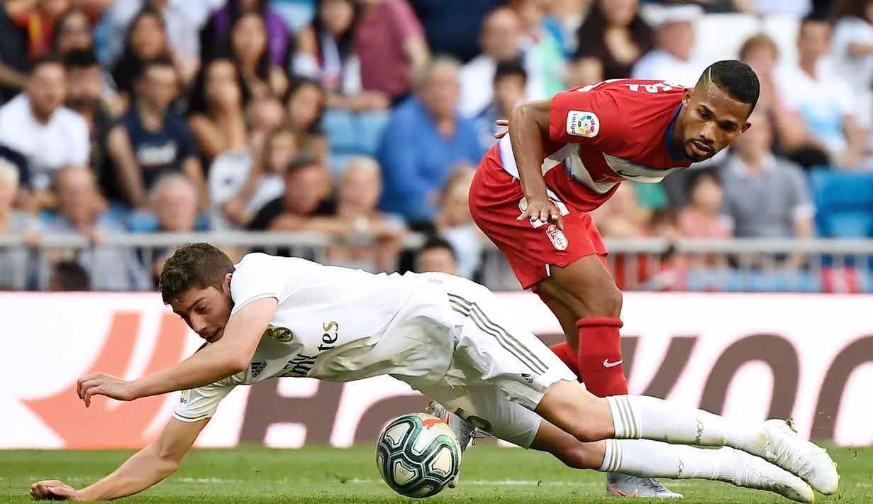 Gelandang Real Madrid, Federico Valverde, dijatuhkan gelandang Granada, Yangel Herrera, pada laga La Liga Spanyol di Stadion Santiago Bernabeu, Madrid, Sabtu (5/10). Madrid menang 4-2 atas Granada. (AFP/Pierre-Philippe Marcou)