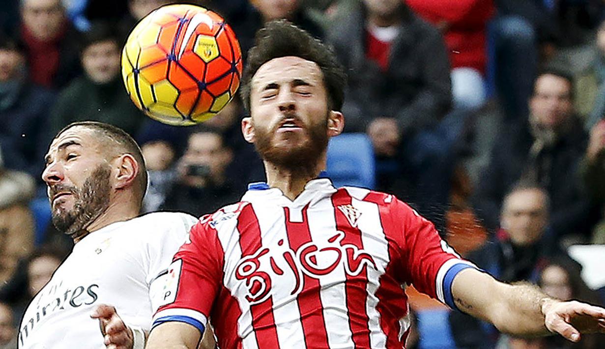 Striker Real Madrid, Karim Benzema, duel udara dengan pemain Sporting Gijon, Alez Menendez. Madrid terpaut empat poin dari Atletico yang berada di puncak klasemen. (Reuters/Andrea Comas)