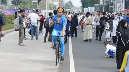 Seorang warga bersepeda di antara peserta Reuni 212 saat Car Free Day (CFD) di kawasan Jakarta, Minggu (2/12). Warga tetap memadati area Car Free Day  dari Bundaran HI-Sudirman meskipun ada aksi Reuni 212. (Liputan6.com/Angga Yuniar)