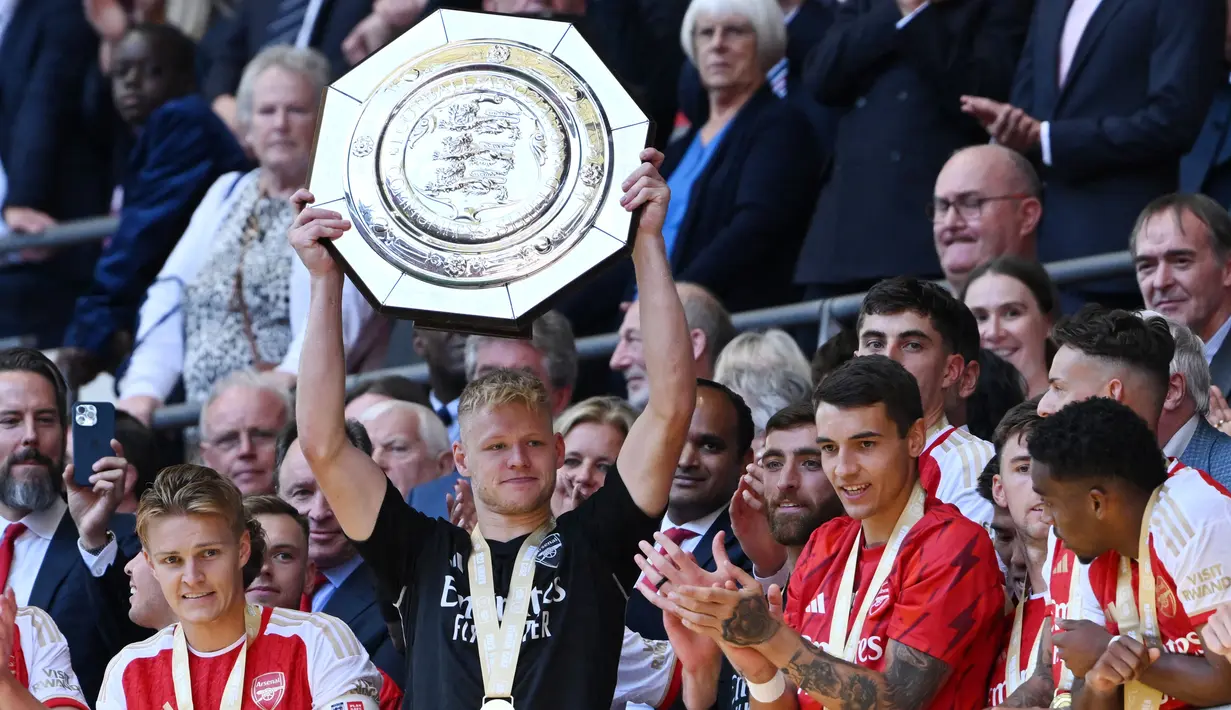 Kiper Arsenal, Aaron Ramsdale, mengangkat trofi Community Shield di Stadion Wembley, London, Minggu (6/8/2023). Arsenal mengalahkan Manchester City 4-1 lewat adu penalti setelah bermain imbang 1-1 selama 90 menit. (AFP/Justin Tallis)