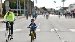 Seorang wanita dan anak kecil mengendarai sepeda di jalan-jalan bebas kendaraan bermotor selama acara CicLAvia di Culver City, Los Angeles, Minggu (3/3). Di Los Angeles, car free day disebut juga CicLAvia. (Chris Delmas/AFP)