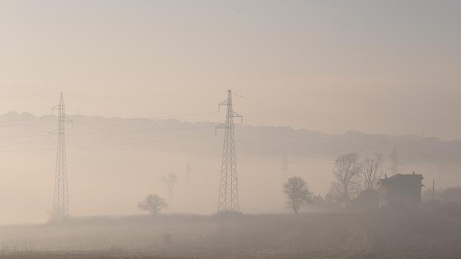 Pohon dan tiang listrik terlihat melalui kabut tebal di kota Pristina (17/12/2019). Selama beberapa bulan terakhir Pristina terdaftar sebagai salah satu kota yang mengalami kualitas udara terburuk di dunia. (AFP/Armend Nimani)