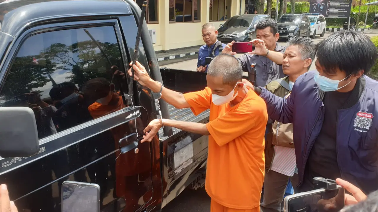 Tersangka AR tengah mempraktekan cara mencuri satu kendaraan pick up bermodalkan bambu tipis yang dibungkus lakban di depan wartawan di Mapolres Garut. (Liputan6.com/Jayadi Supriadin)