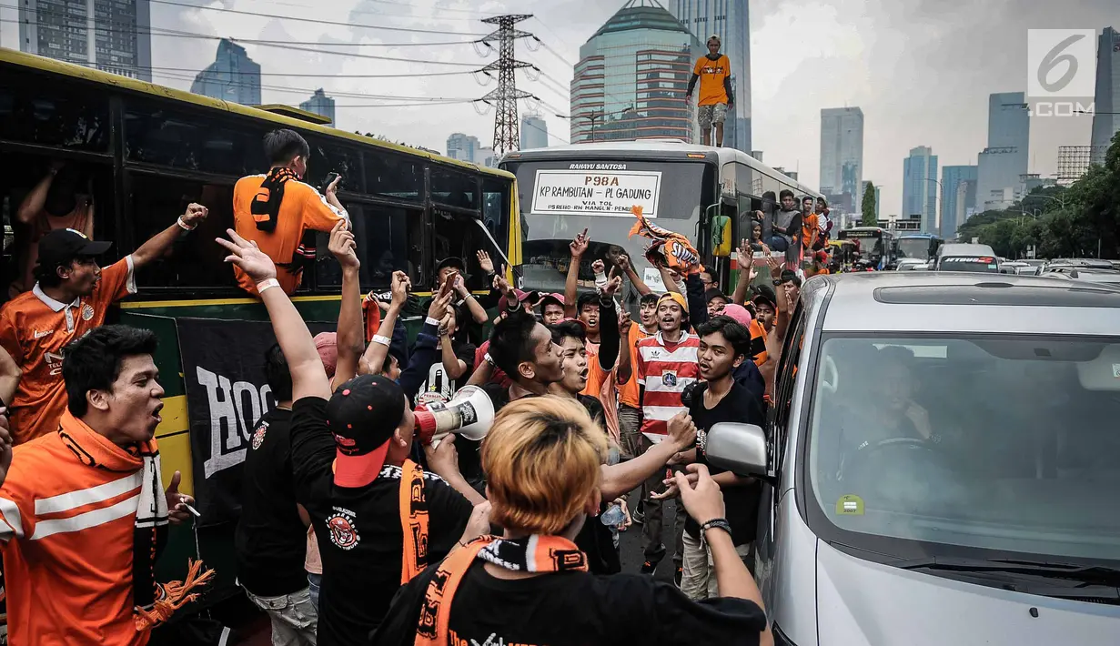 Suporter Persija bersorak saat menuju stadion Gelora Bung Karno, Jakarta, Minggu (9/12). Antusiasme ribuan suporter Persija bersiap mendukung tim kesayangannya bertanding melawan Mitra Kukar. (Liputan6.com/Faizal Fanani)