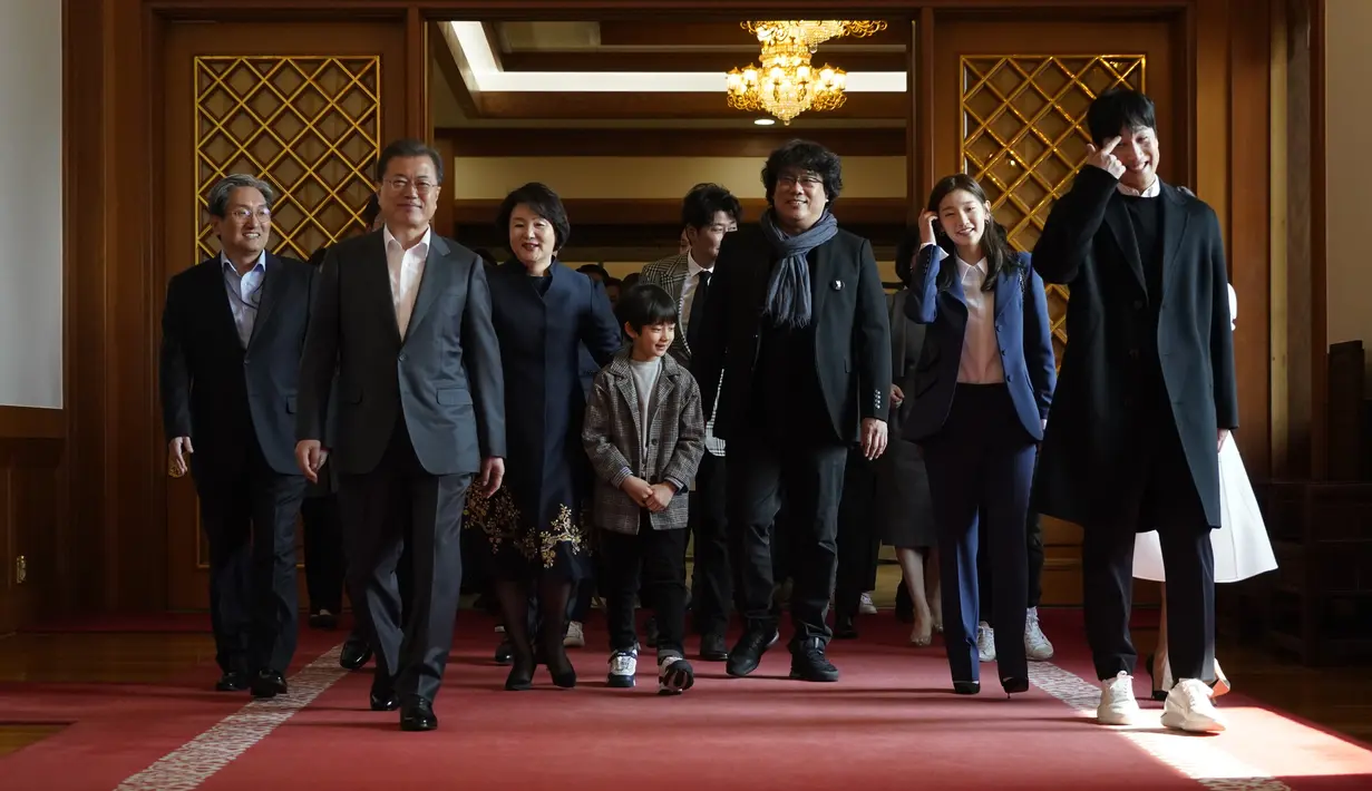 Sutradara Bong Joon Ho  dan Presiden Korea Selatan Moon Jae-in berjalan untuk makan siang di Blue House, Seoul, Kamis (20/2/2020). Presiden Moon mengundang Sutradara Bong Joon Ho dan seluruh tim untuk merayakan kemenangan Parasite yang membawa pulang empat Piala Oscar 2020. (KIM HONG-JI/AFP)