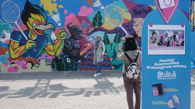 Indonesia Open 2019 memilih tema Sport-art-ainment. Salah satu pengunjung yang sedang berfoto di mural di Istora Senayan (Liputan6.com/Luthfie Febrianto)