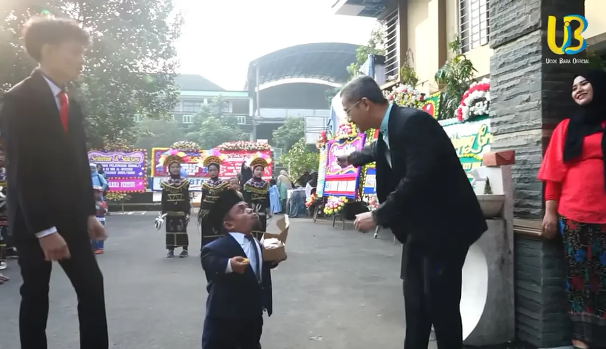 Tiba di sekolah putranya, kehadiran pemeran sinetron Anak Sekolahan itu menarik perhatian para wali murid yang hadir. Potret kehadiran Ucok Baba bersama putranya. Ucok diarahkan untuk lewat pintu yang lain pintu yang didekatnya khusus untuk yang wisuda. [Youtube/Ucok Baba official]