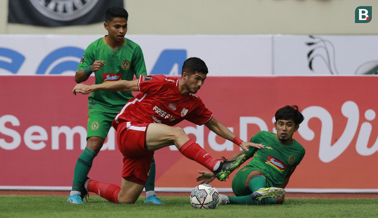 Dua pemain PSS Sleman berebut bola dengan pemain Persis Solo, Kevin Gomes De Oliveira (tengah) dalam lanjutan pertandingan babak penyisihan Grup A Piala Presiden 2022 di Stadion Manahan, Solo, Jawa Tengah, Sabtu (11/6/2022). (Bola.com/Arief Bagus)