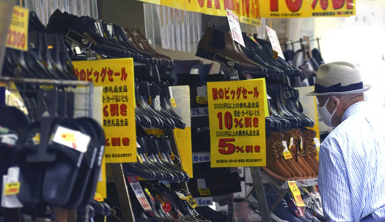 Seorang pria yang mengenakan masker  untuk membantu mengekang penyebaran COVID-19 melihat sepatu di sebuah toko di Tokyo, Jepang, Senin (2/11/2020). Tokyo mengonfirmasi lebih dari 80 kasus baru COVID-19 pada 2 Oktober 2020. (AP Photo/Eugene Hoshiko)