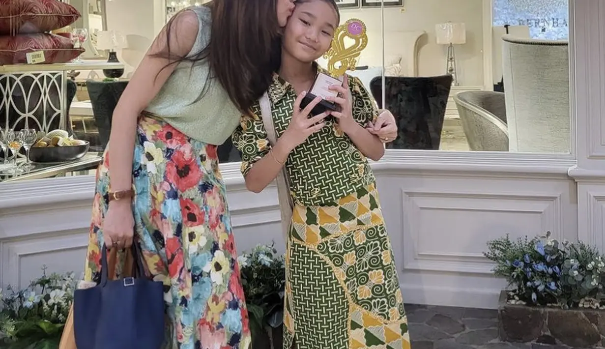 Ayu tampil mengenakan atasan sleevesless hijau sage yang dipadukan dengan midi skirt motif bunga warna-warni.  (@ayutingting92)