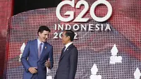 Perdana Menteri Kanada Justin Trudeau berbicara dengan Presiden Indonesia Joko Widodo atau Jokowi yang menyambutnya pada hari pertama Konferensi Tingkat Tinggi (KTT) G20 di Nusa Dua, Bali, Selasa (15/11/2022) pagi. Jokowi menyampaikan ucapan selamat datang di lobi depan venue utama KTT G20. (KEVIN LAMARQUE / POOL / AFP)