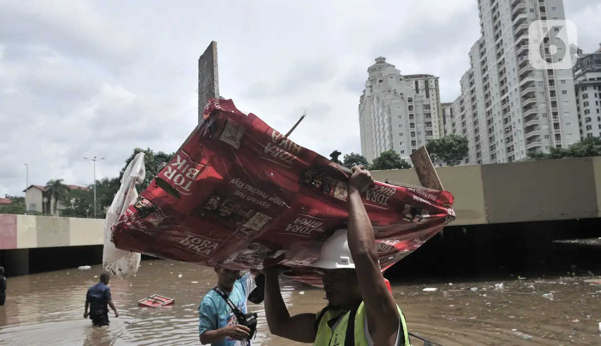 Petugas Pusat Pengelolaan Kompleks (PPK) Kemayoran membersihkan sampah yang muncul akibat banjir di Underpass Kemayoran, Jakarta, Minggu (2/2/2020). Selain melumpuhkan akses, banjir setinggi hingga 5 meter tersebut menyebabkan sampah memenuhi Underpass Kemayoran. (merdeka.com/Iqbal S. Nugroho)