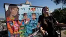 Seniman Brasil, Luna Buschinelli berpose dengan latar belakang mural berjudul 'Contos' di dinding gedung sekolah Rio de Janeiro, (19/6). Karya gadis 19 tahun itu memecahkan rekor dunia sebagai mural terbesar yang dibuat oleh wanita. (AP/Silvia Izquierdo)