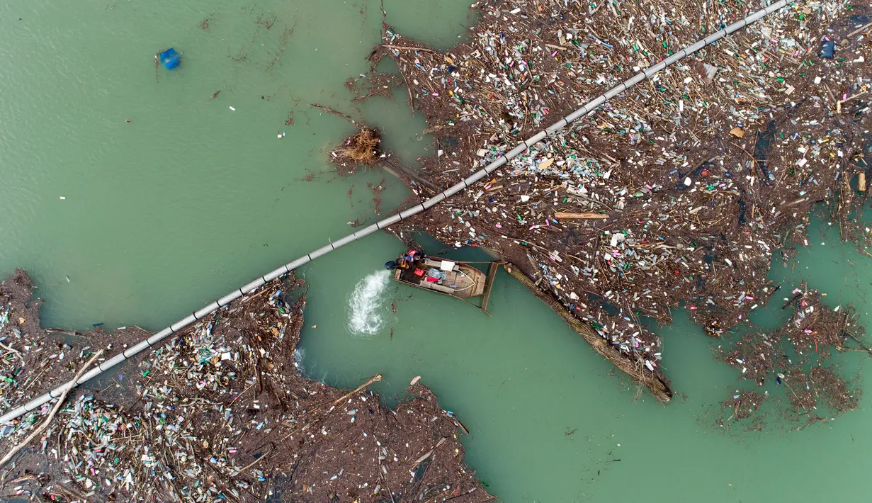Foto udara memperlihatkan pekerja perusahaan utilitas mendorong limbah ke tepi Sungai Lim dekat Priboj, Serbia, 30 Januari 2023. Botol plastik, papan kayu, tong berkarat, dan sampah lainnya dari tempat pembuangan sampah tepi sungai yang tidak diatur dengan baik terakumulasi selama air pasang. (AP Photo/Armin Durgut)