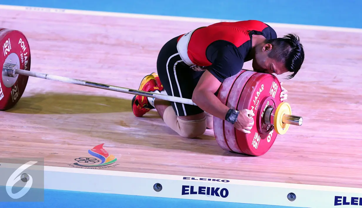 Lifter Jawa Barat, Deni mencium barbel usai berhasil mengangkat beban 183kg clean and jerk kelas 69kg PON XIX Jabar di Gymnasium Si Jalak Harupat, Kab Bandung, Rabu (21/9). Deni meraih emas dengan total angkatan 328kg. (Liputan6.com/Helmi Fithriansyah)