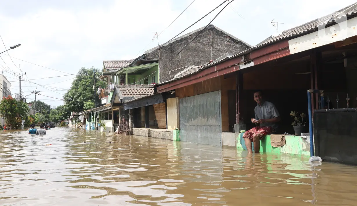 Warga duduk di pagar rumah saat banjir merendam perumahan Ciledug Indah, Tangerang, Banten, Kamis (2/1/2020). Memasuki hari kedua, kondisi perumahan tersebut masih tergenang banjir setinggi dada orang dewasa. (Liputan6.com/Angga Yuniar)