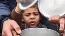 Puluhan ribu anak-anak menjadi korban perang yang sedang berlangsung antara Israel dan Hamas di wilayah Gaza. Tampak dalam foto, seorang anak laki-laki Palestina berusaha mendapatkan makanan dari lokasi distribusi di Kota Gaza pada 19 November 2024. (Omar AL-QATTAA/AFP)