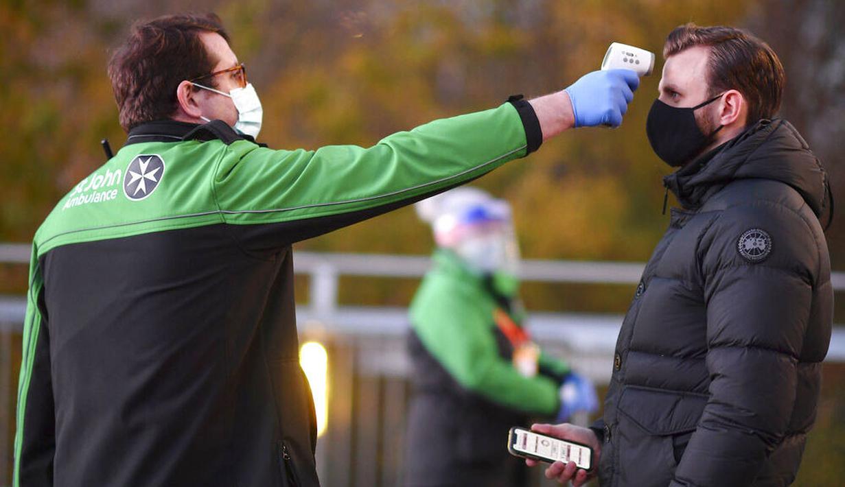 Petugas memeriksa suhu tubuh suporter West Ham United sebelum menyaksikan pertandingan melawan Manchester United di Stadion London, Sabtu (5/12/2020). (Justin Setterfield/Pool Via AP)