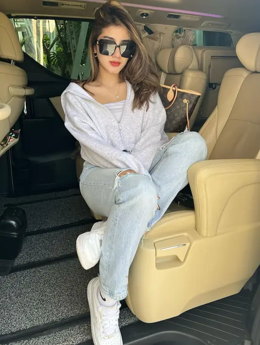 Ghea Youbi saat berpose di dalam mobil. Ia tampil dengan celana jeans serta kaca mata hitam dan sepatu berwarna putih. Kemanapun Ghea pergi, kaca mata hitam selalu melekat di wajahnya. (Instagram/gheayoubi)