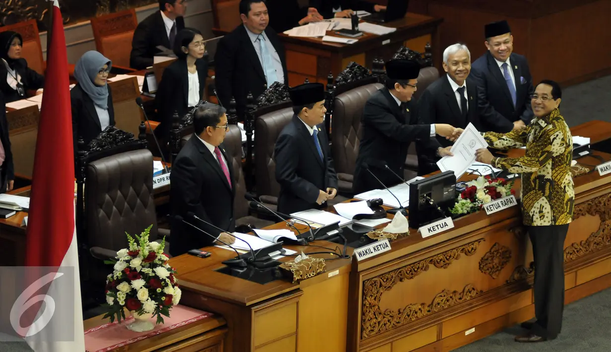 Wakil Ketua Badan Legislasi (Baleg) Firman Soebagyo memberikan laporan ke Ketua Rapat Taufik Kurniawan (tengah) saat Rapat Paripurna ke-30 DPR RI masa persidangan V Tahun sidang 2015-2016, Senayan, Jakarta, Senin (20/6). (Liputan6.com/Johan Tallo)