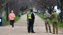 Petugas kepolisian dan tentara berpatroli di jalur lari yang populer di Melbourne, Selasa (4/8/2020). Melbourne memasuki pembatasan Tahap 4 dengan aturan yang lebih ketat sebagai upaya untuk membatasi pergerakan masyarakat dan penyebaran COVID-19. (William WEST / AFP)