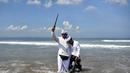 Seorang pria memegang keris saat sembahyang upacara Melasti di pantai Petitenget dekat Denpasar, di pulau resor Bali, Indonesia pada 19 Maret 2023. (AFP/SONNY TUMBELAKA)