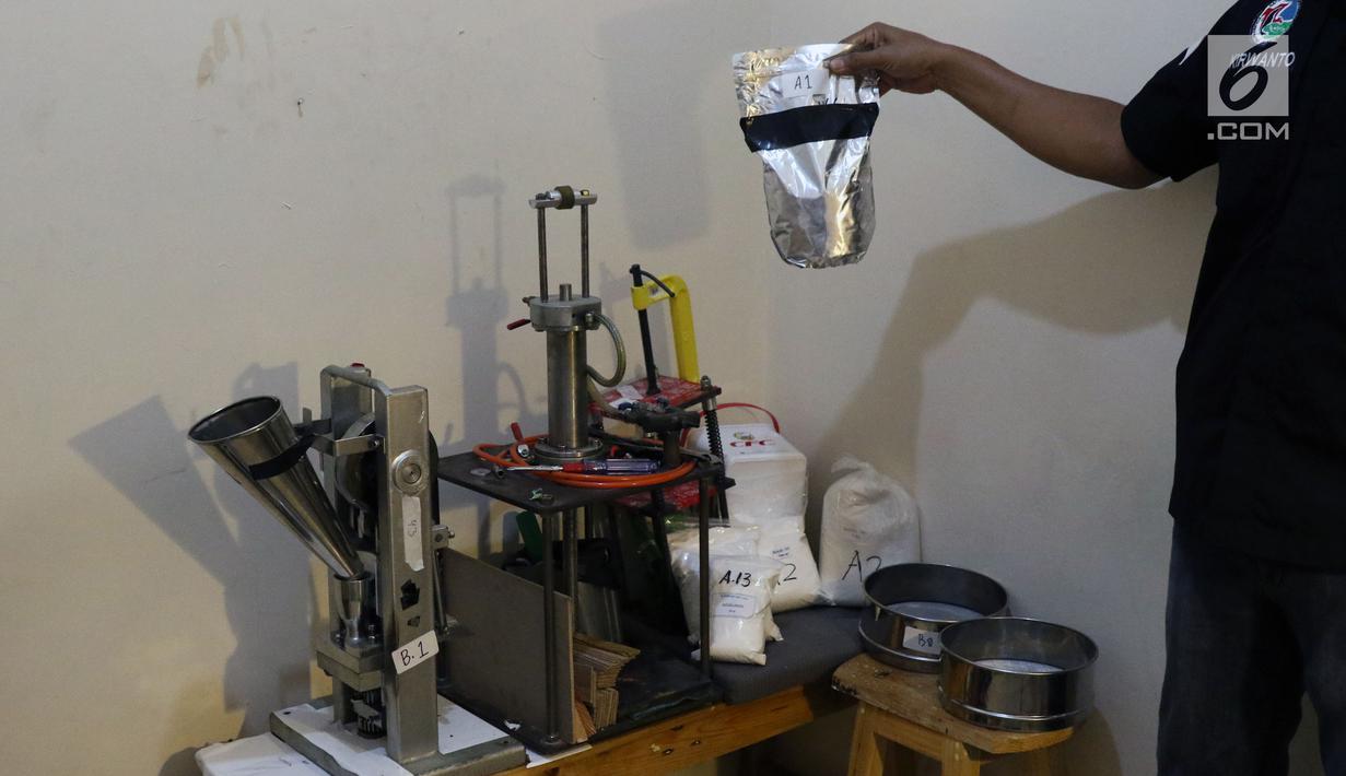 Petugas menunjukkan barang bukti alat pencetak pil ekstasi di sebuah perumahan di Kawasan Pondok Rajeg, Cibinong, Jawa Barat, Senin (24/9). Polisi juga menahan tiga tersangka dan sejumlah barang bukti terkait. (Liputan6.com/Helmi Fithriansyah)