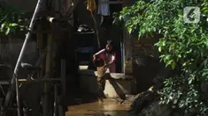 Seorang anak membersihkan rumah dari sisa lumpur di Bukit Duri, Jakarta, Jumat (29/10/2021). Hujan dengan intensitas tinggi beberapa hari lalu membuat aliran sungai ciliwung meluap yang merendam sebagian rumah warga yang tinggal di bantaransungai  tersebut. (merdeka.com/Imam Buhori)