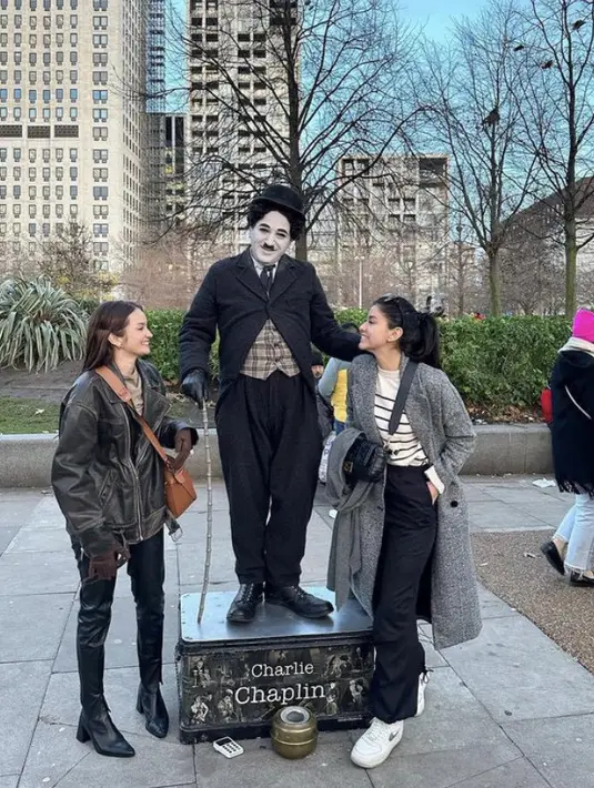 Medina dan Enzy berfoto dengan Charlie Chaplin. Medina dengan coat abu dipadukan celana hitam. Sedangkan Enzy tampil dengan busana latex hitam Credit: (@medinadinaaa)