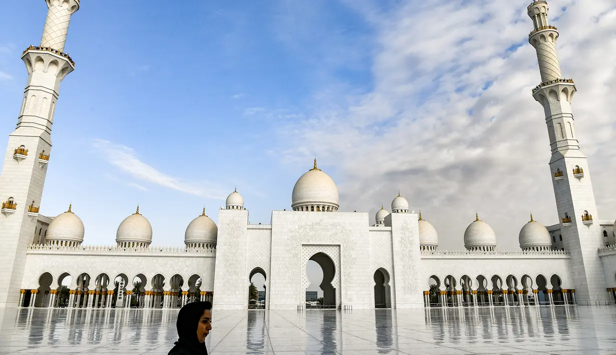 Seorang wanita melewati halaman Masjid Agung Sheikh Zayed di Abu Dhabi, Uni Emirat Arab. Masjid ini dibangun oleh presiden pertama Uni Emirat Arab, yaitu Sheikh Zayed bin Sultan Al Nahyan. (Photo by Vincenzo PINTO / AFP)
