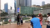 Sejumlah warga berdiri di viewing deck untuk berfoto dengan latar tugu patung Selamat Datang di Bundaran HI. (Merdeka.com)