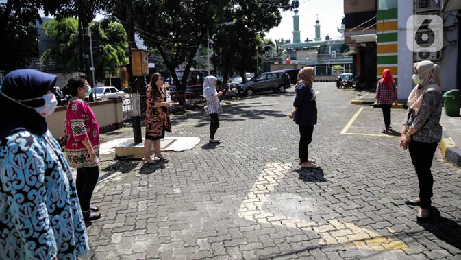 Sejumlah pegawai berjemur di bawah sinar matahari di Kawasan Fatmawati, Jakarta, Selasa (31/3/2020). Berjemur diri di bawah sinar matahari saat pagi merupakan salah satu upaya yang paling sederhana untuk menjaga kesehatan selama wabah virus COVID-19. (Liputan6.com/Faizal Fanani)