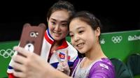 Pesenam lantai Korea Selatan Lee Eun-ju dan pesenam Korea Utara, Hong Un-jong, menyuguhkan momen singkat bersatunya duo Korea, dengan cara berfoto selfie bersama. (Reuters)