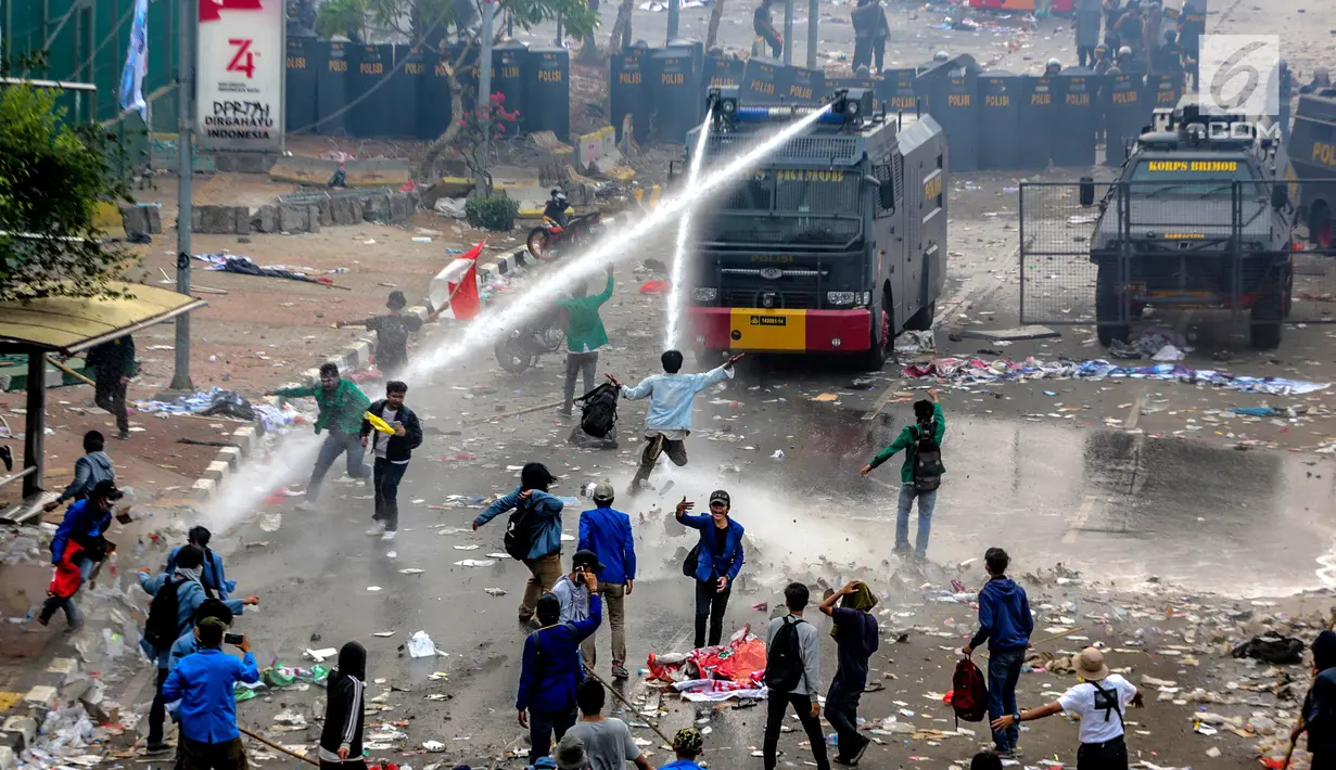 Polisi menyemprotkan air menggunakan water cannon ke arah mahasiswa saat demonstrasi menolak pengesahan RUU KUHP dan revisi UU KPK di depan Gedung DPR, Jakarta, Selasa (24/9/2019). Polisi menyemprotkan air ke arah mahasiswa karena menolak untuk dibubarkan. (Liputan6.com/Faizal Fanani)